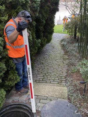 Consultant measuring elevation at associated pump station manhole