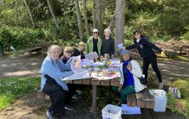A group of women sitting at a picnic table in a park. 
