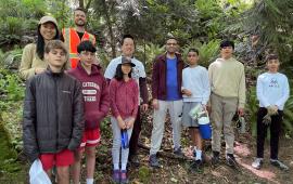 A group of volunteers posing in a forest on a sunny day.