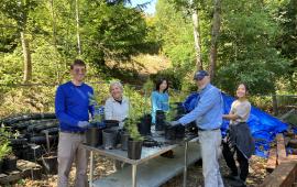 A group of volunteers posing around a table with plants in their hands.