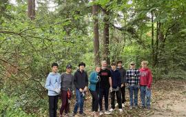 A group of volunteers posing alongside a trail in front of a forest.