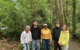 A small group of volunteers, posing in front of a a forest.