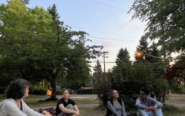 Four people sitting in the park, looking up at the sky. 