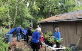 A group of volunteers standing around a table, working on potted plants. 