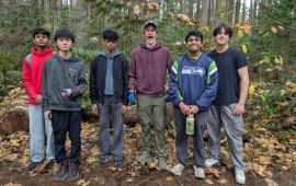 A group of volunteering posing in the park on a rainy day.