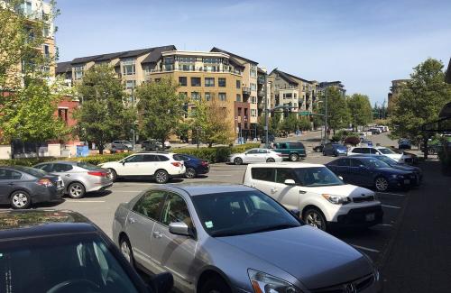 A downtown parking lot is filled with cars on a sunny day.