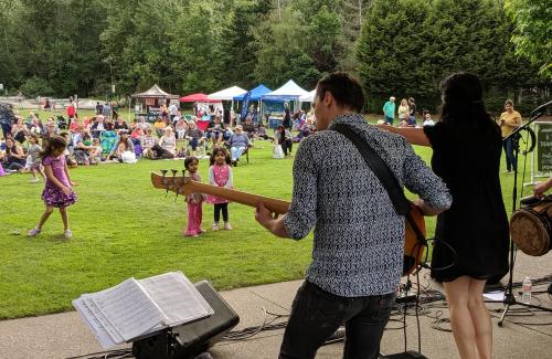 A band plays to a lively audience of all ages at a concert in the park