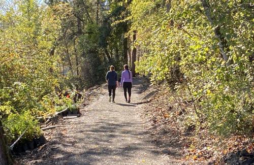 Two women walk on a forested, shoreline trail on a sunny fall day in Luther Burbank Park
