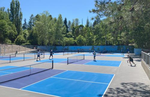 Groups of people play pickleball on blue and gray courts at Luther Burbank Park