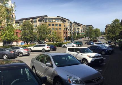 A downtown parking lot is filled with cars on a sunny day.