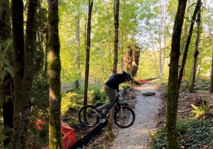 A professional bike rider performs a trick jump at a mountain biking course on a sunny fall day