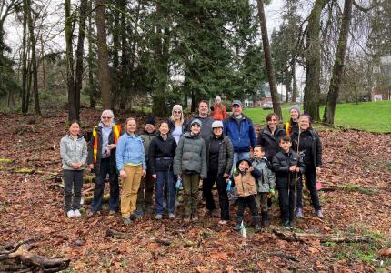 Group photo of people various ages posing in front of a forest.