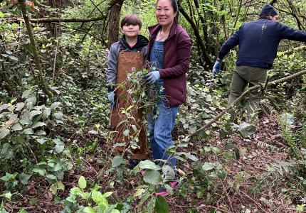 Two volunteers smiling while standing in a forest.