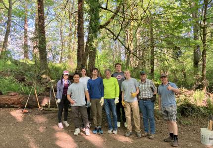A group of volunteers posing in front of a forest.