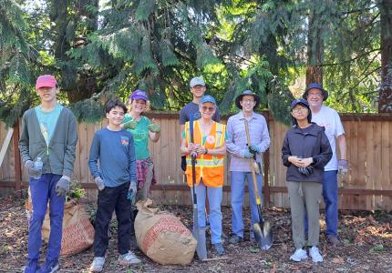 Volunteers smiling standing in front of a fence. 