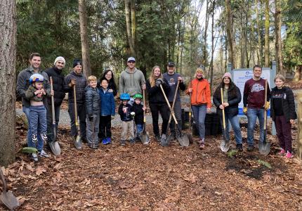 A group of people smiling and holding shovels.