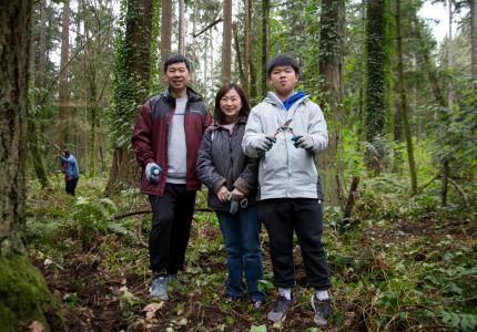 Family poses with tools in front of a forest of trees.
