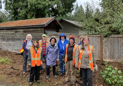 A group of Forest Stewards posing in front of a fence. 