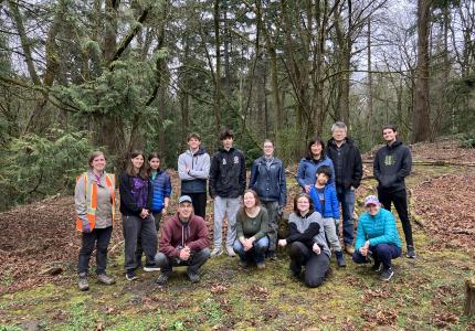 A group of volunteers posing in front of a forest