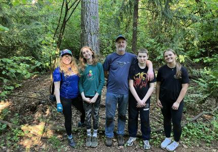 A group of volunteers posing in front of a forest. 