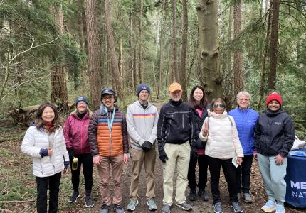 A group of people smiling and posing in front of a forest