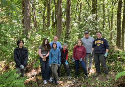 A group of volunteers posing in front of a forest.