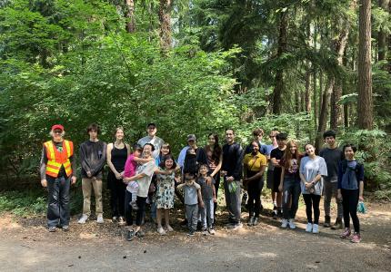 A large group of volunteers posing in front of the forest.