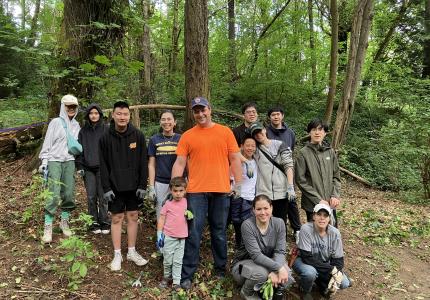 A group of volunteers posing in front of a forest