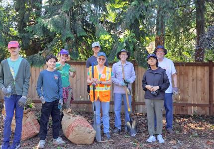 Volunteers posing on a trail in front of a fence. 