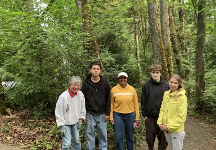 A group of volunteers posing in front of a forest.