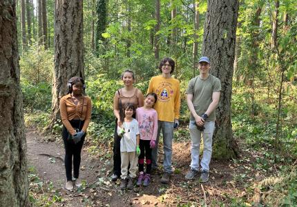 A group of volunteers posing in front of a forest. 