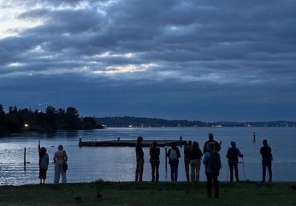 silhouette of people standing in front of a lake. 