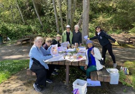 A group of women sitting at a picnic table in a park. 