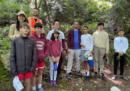 A group of volunteers posing in a forest on a sunny day.