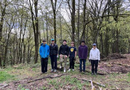 A group of volunteers standing in front of a forest. 