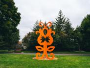 A whimsical and bright orange sculpture blooms in a sculpture park
