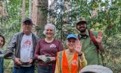 4 volunteers smiling in the woods.