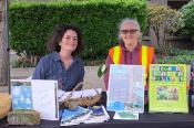 Two people sitting behind a table with pamphlets on ecological restoration.