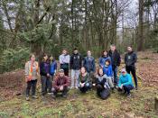 A large group of volunteers posing in front of a forested park on a cloudy day.