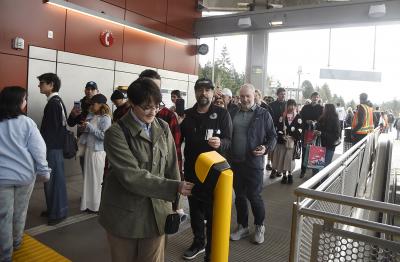 Riders tap their ORCA cards to be among the first to board a light rail train at Mercer Island Station