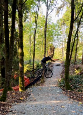 A professional bike rider performs a trick jump at a mountain biking course on a sunny fall day
