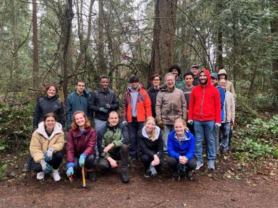 A group of people posing in front of a forest
