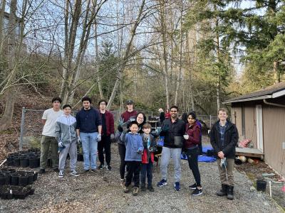 A group of people smiling, standing in front of a forested background. 