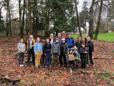 Group photo of people various ages posing in front of a forest.