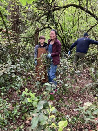 Two volunteers smiling while standing in a forest.