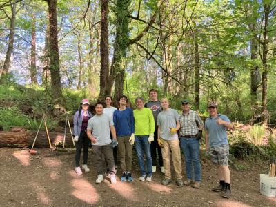 A group of volunteers posing in front of a forest.