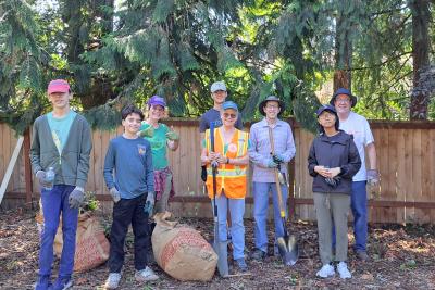 Volunteers smiling standing in front of a fence. 