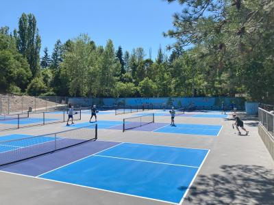 Groups of people play pickleball on blue and gray courts at Luther Burbank Park