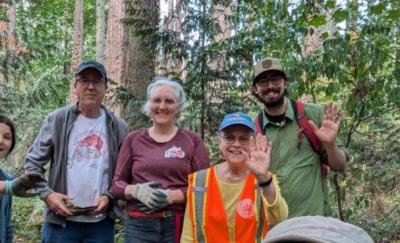 A small group of volunteers posing in the forest