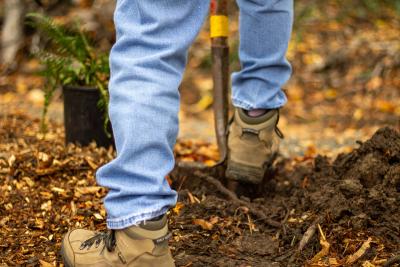 Feet standing on a shovel in the ground. 